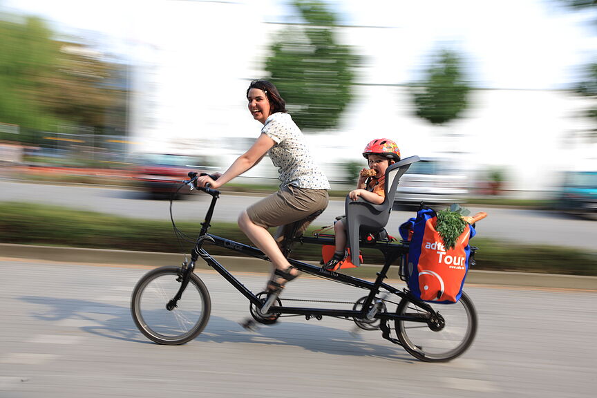 Frau mit Kind und Einkauf auf Lastenrad Frau mit Kind und Einkauf auf Lastenrad
